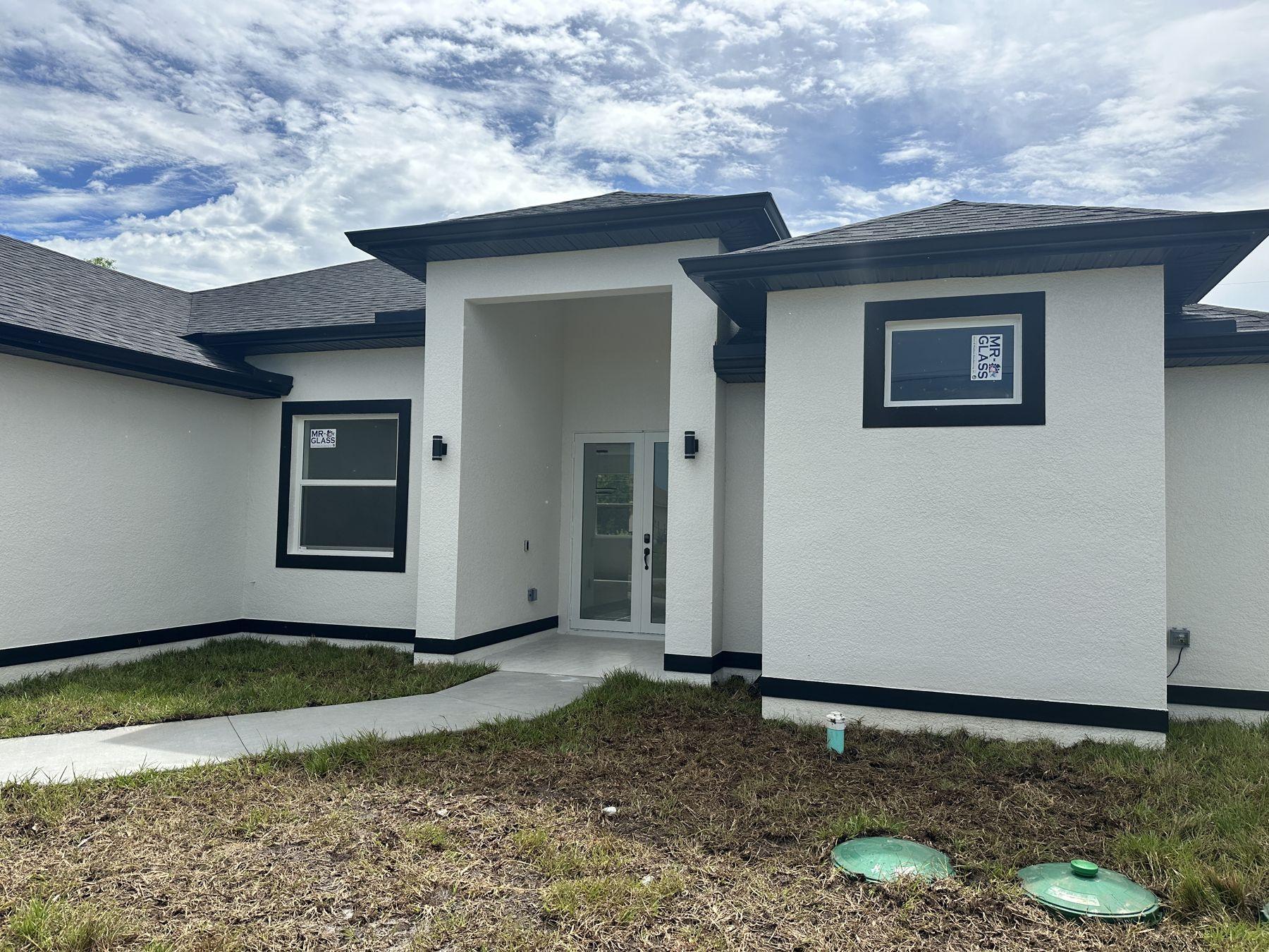 New single-family home with dark trim built by DMG Builders in Lehigh Acres, FL
