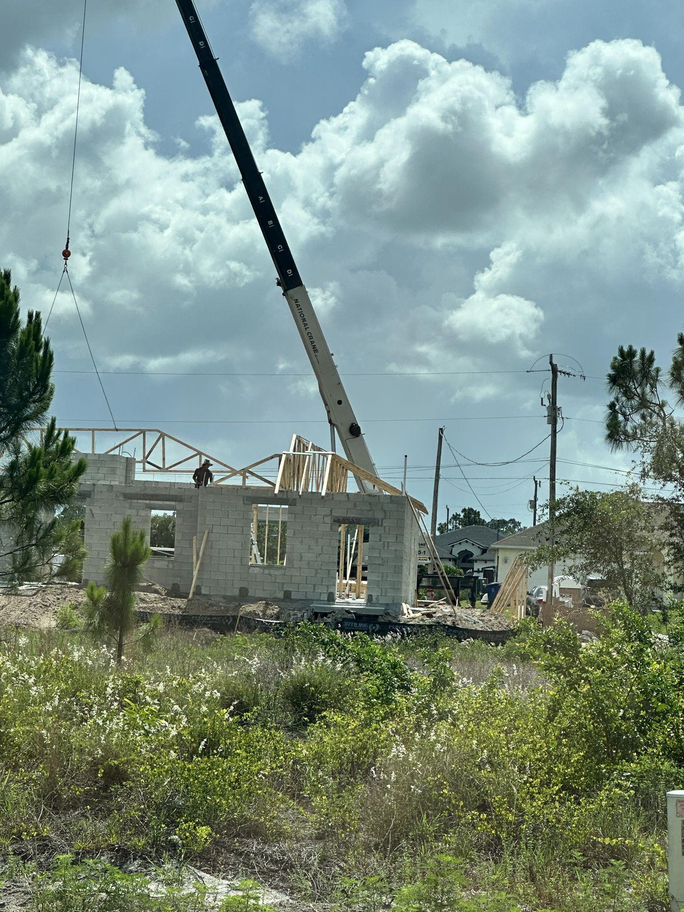 Crane setting roof trusses on a new block home