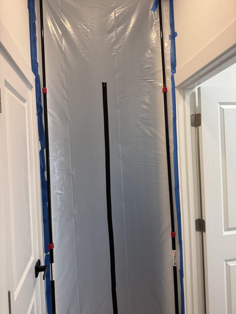 Plastic dust barrier with zipper door taped around a doorway