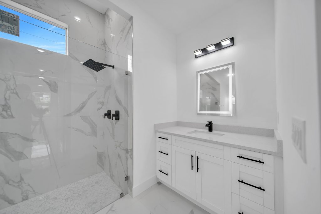 Remodeled bathroom with frameless glass walk-in shower and quartz vanity by DMG Builders
